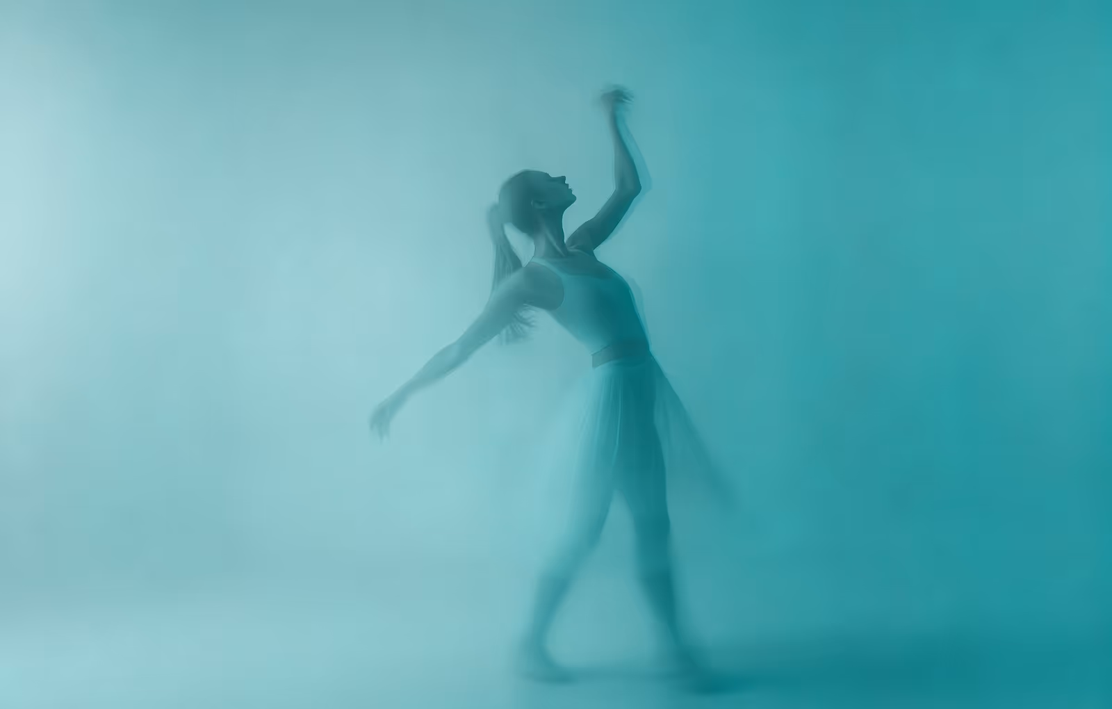 Silhouetted dancer in motion with blurred teal background and soft lighting.
