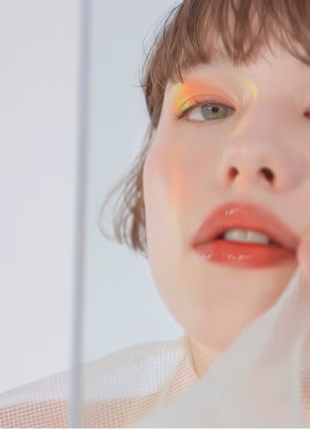 Close-up of a woman with bright orange and yellow eyeshadow and glossy coral lipstick.